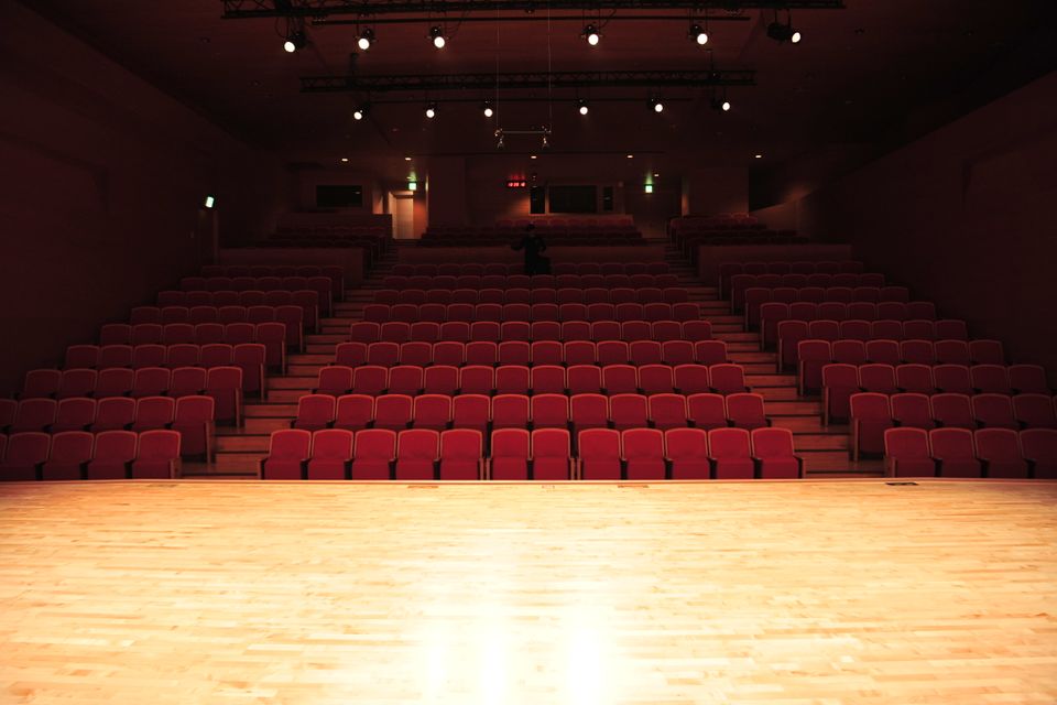Scène éclairée et fauteuils rouges dans un théâtre — illustration